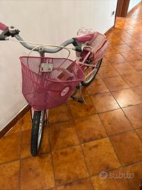 Bicicletta rosa con cestino e sacca