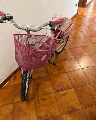 Bicicletta rosa con cestino e sacca