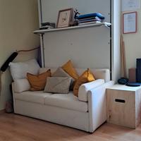 Divano letto a scomparsa a muro in libreria.