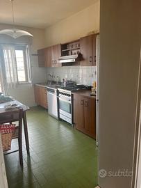Cucina con elettrodomestici, tavolo, sedie