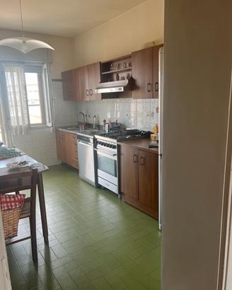 Cucina con elettrodomestici, tavolo, sedie