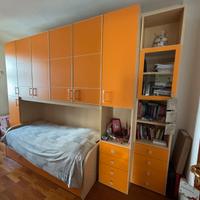 Camera a ponte arancione doppio letto e libreria