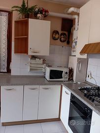 cucina con sedie mensole e divano