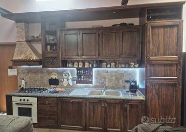 Cucina con frigo, lavastoviglie, tavolo e panche