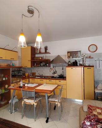 cucina con tavolo e 4 sedie, divano a due posti