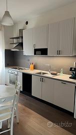 Cucina con elettrodomestici e tavolo con 4 sedie