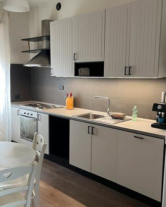 Cucina con elettrodomestici e tavolo con 4 sedie