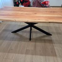 Tavolo in legno con piedi in ferro battuto nero.