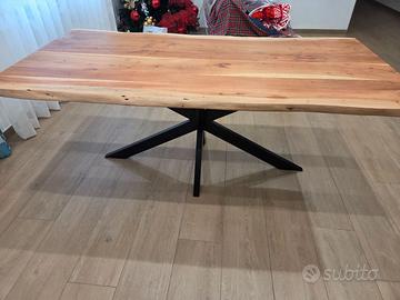 Tavolo in legno con piedi in ferro battuto nero.