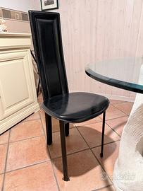 Tavolo in cristallo e sedie in cuoio