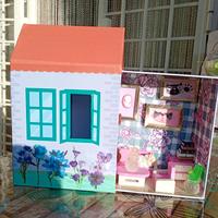 Scatola casa con mobili e gattino addormentato.