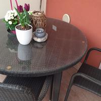 Tavolo rotondo in vetro e sedie in rattan marrone