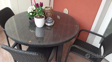 Tavolo rotondo in vetro e sedie in rattan marrone