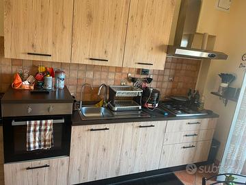 Cucina lineare con elettrodomestici, tav e  sedie.