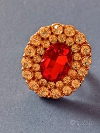 anello dorato con una grande pietra rossa