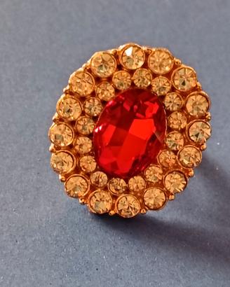 anello dorato con una grande pietra rossa