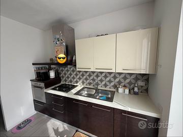 Cucina completa con tavolo e elettrodomestici