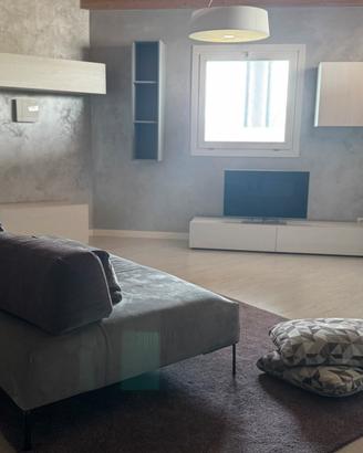 Sala con divano, tappeto, cuscini, tv, lampada