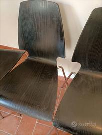 Quattro sedie di legno nere e acciaio