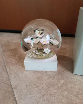 Sfera di vetro con farfalla su ramo fiorito