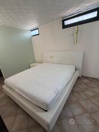 Letto, comò e comodini di colore bianco.