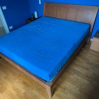 Letto matrimoniale in legno con rete a doghe.