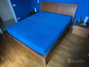 Letto matrimoniale in legno con rete a doghe.