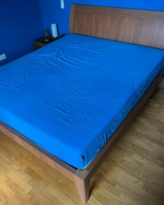 Letto matrimoniale in legno con rete a doghe.