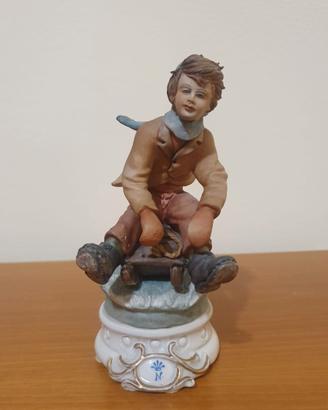 Statua porcellana Capodimonte bimbo su slitta