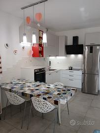 Cucina con elettrodomestici, induzione e tavolo