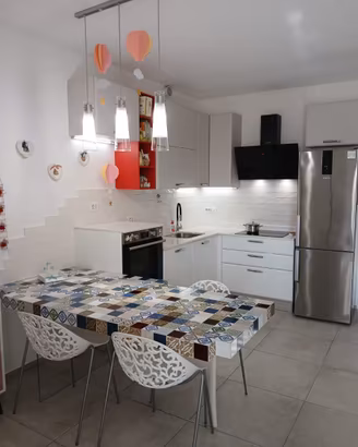 Cucina con elettrodomestici, induzione e tavolo